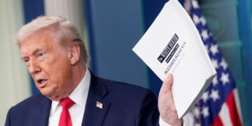 CARI CUAN: Presiden Donald Trump saat melempar buku pencapaian pemerintah AS. (Foto Ilustrasi: REUTERS/Nathan Howard)