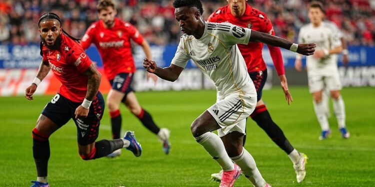LAGA DRAMATIS: Vinicius Junior berebut bola dengan Valentin Rosier dalam laga Liga Spanyol antara Osasuna vs Real Madrid di Estadio El Sadar pada Minggu (22/2/2026). (Foto: (c) AP Photo/Miguel Oses)