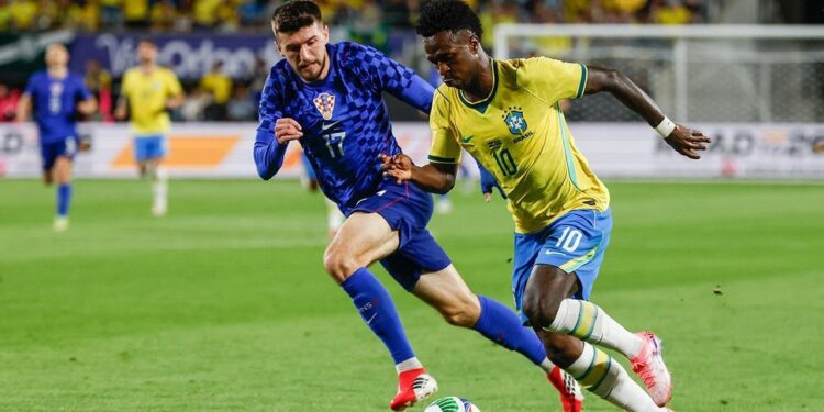 HASIL POSITIF: Vinicius Junior dikawal oleh Petar Sucic dalam laga uji coba internasional antara Brasil vs Kroasia di Camping World Stadium, Florida pada Rabu (1/4/2026). (Foto: (c) AP Photo/Kevin Kolczynski)