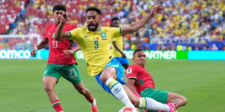 Hasil Imbang 1-1 Lawan Maroko Jadi Pelajaran Penting Bagi Brasil 1 DI LUAR HARAPAN: Pemain Brasil Matheus Cunha (tengah) berduel dengan pemain Maroko Soufiane Rahimi dalam pertandingan Grup C Piala Dunia 2026 pada Minggu (14/6/2026). (Foto: (c) AP Photo/Yuki Iwamura)