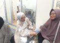 CEK KESEHATAN: Apoteker Alifia Maya Fatmawati (tengah) mengecek tekanan darah salah seorang peserta bakti sosial cek gula darah gratis dalam rangkaian grand opening Apotek GWS Farma di Jalan Raden Fatah, Parung Serab, Ciledug, Kota Tangerang, Banten pada Minggu (31/5/2026) malam. (FOTO: UNSIYAH SANGIDAH/KORANINDOPOS.COM)