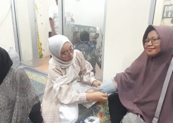 CEK KESEHATAN: Apoteker Alifia Maya Fatmawati (tengah) mengecek tekanan darah salah seorang peserta bakti sosial cek gula darah gratis dalam rangkaian grand opening Apotek GWS Farma di Jalan Raden Fatah, Parung Serab, Ciledug, Kota Tangerang, Banten pada Minggu (31/5/2026) malam. (FOTO: UNSIYAH SANGIDAH/KORANINDOPOS.COM)