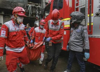 PROSES EVAKUASI: Petugas Sudin Gulkarmat Jakarta Timur mengevakuasi jenazah korban saat memadamkan api di Kelurahan Dukuh, Kramat Jati, Jakarta Timur pada Minggu (2/8/2026). (AFP/SYNATRIA RESPATI via CNNI)