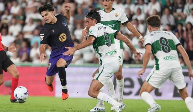 DUEL SENGIT: Pemain Barcelona Xavi Espart berebut bola dengan pemain Elche Federico Redondo dalam laga La Liga Spanyol antara Elche vs Barcelona di Elche, Spanyol pada Minggu (23/8/2026). (Foto: (c) AP Photo/Alberto Saiz)