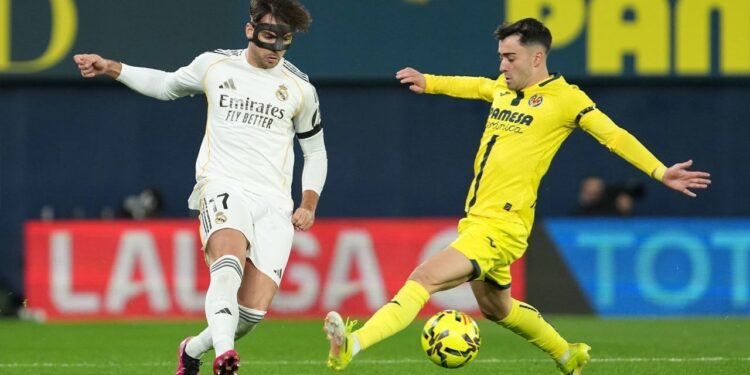 Raul Asencio Tolak Transfer Karena Ingin Bertahan di Real Madrid 1 LINI BELAKANG: Pemain Real Madrid Raul Asencio (kiri) berebut bola dengan pemain Villarreal Alberto Moleiro pada laga La Liga/Liga Spanyol antara Villarreal vs Real Madrid pada 24 Januari 2026. (Foto Ilustrasi: (c) AP Photo/Alberto Saiz)
