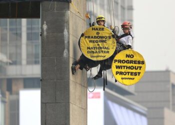 AKSI SPEKTAKULER: Dua aktivis Greenpeace Indonesia saat memanjat Patung Selamat Datang, Bundaran HI, Jakarta Pusat pada Selasa (20/10/2026) pagi dengan cara single rope technique. (Foto: IST)