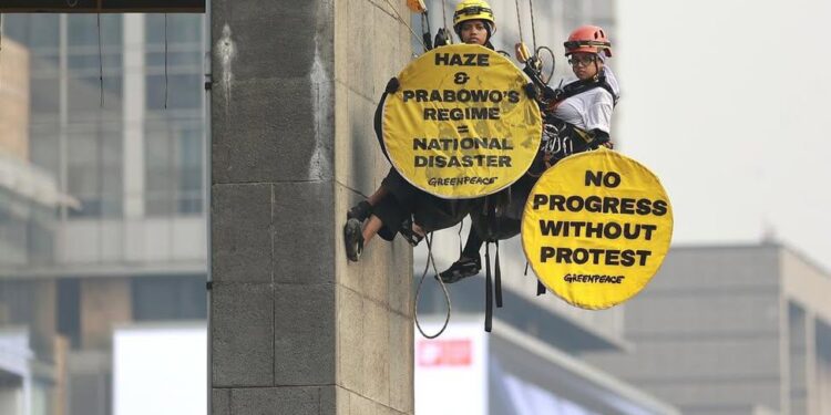 AKSI SPEKTAKULER: Dua aktivis Greenpeace Indonesia saat memanjat Patung Selamat Datang, Bundaran HI, Jakarta Pusat pada Selasa (20/10/2026) pagi dengan cara single rope technique. (Foto: IST)